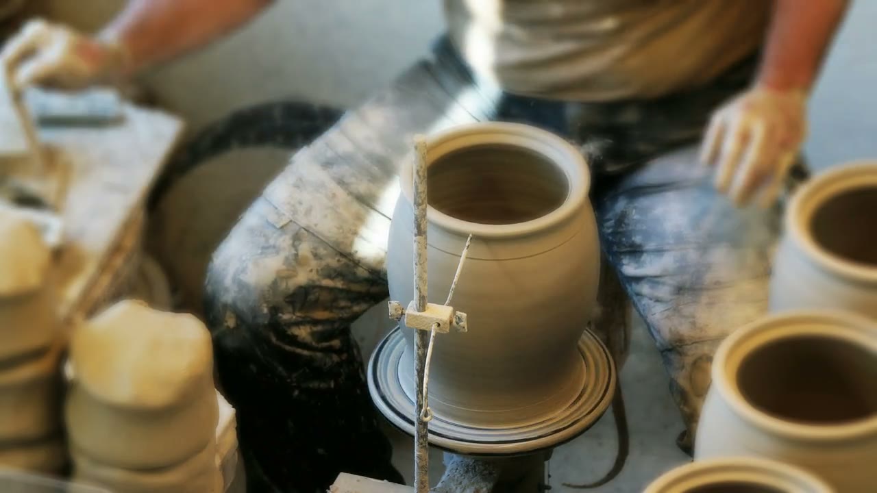 Frisch gedrehter Topf auf der Töpferscheibe, daneben weitere Rohlinge